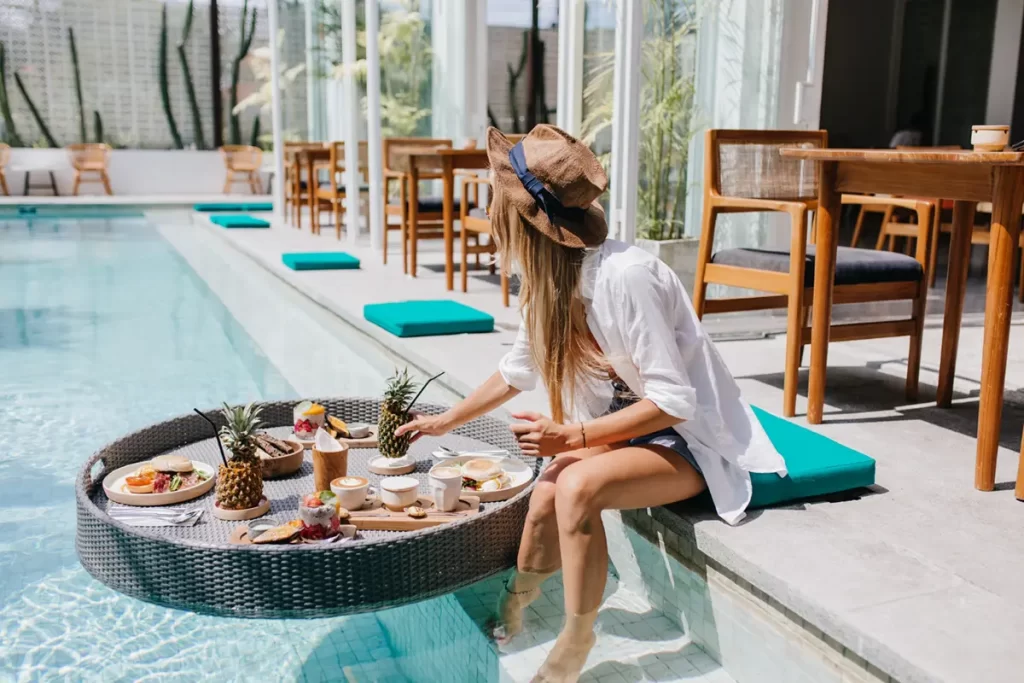 woman in white shirt relaxing with cocktail and food in pool.